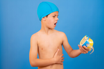 Young boy with swimmer cap and diving goggles over blue background