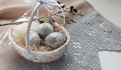 Easter eggs in a wicker basket by the window on a tablecloth
