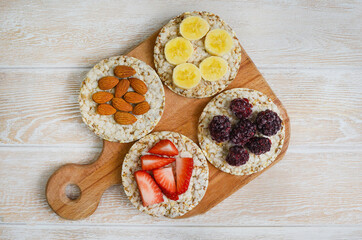 Obraz na płótnie Canvas cereal breakfast crisp breads with strawberry, almonds nuts, banana fruit and blackberry on wooden cutting board top view flat lay