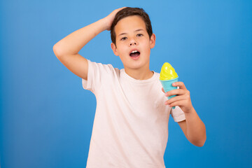 Happy boy holding ice cream cone over blue background