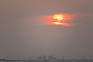  red sun in the sky and evening clouds are over Tangyard. In the petrochemical industry .The front is sea and white waves.