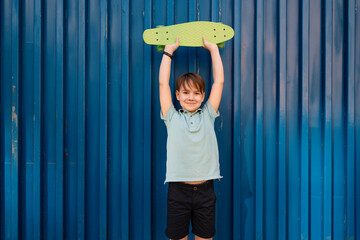 Portrait Young cool smiling BOY in blue polo posing with PENNY BOARD in the hands on a blue background