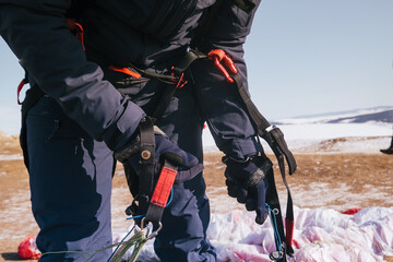 Tourist paraglider climbing mountain above the winter lake Baikal
