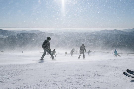 Strong wind and Blizzard in ski resort, skiers and snowboarders on the slop