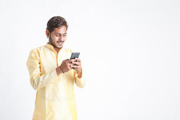 Young indian man in tradition wear and using smartphone on white background.