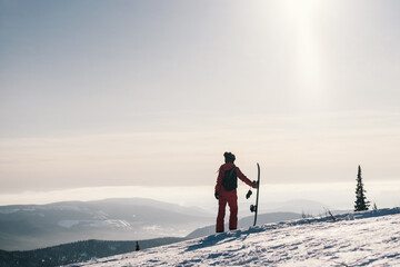 Female with snowboard. Snowboarder walking on snowy slop watching beautiful atmospheric mountain...