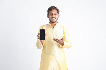 Young indian man in tradition wear and showing smartphone screen on white background.