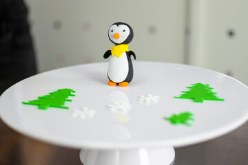 On white plate presented penguin, Christmas trees, and snowflakes. Fondant figures. Pastry shop....