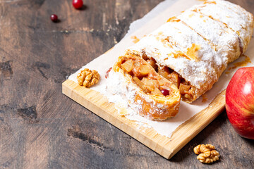 homemade fragrant strudel with apples and cinnamon on a plate on a wooden background with space for text