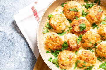 meatballs in white sauce in a frying pan on a gray background, comfortable homemade healthy food