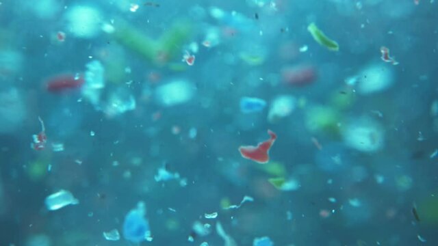 microplatics in water. plastic fragments or particles in ocean. ocean pollution by single-use plastics. environment, ecology, water, earth, slow motion