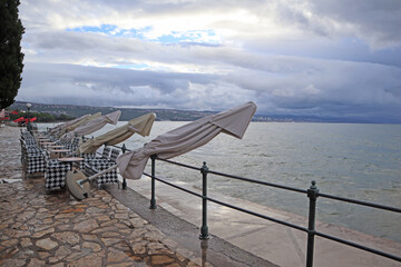 Obraz premium Scenic view of the seaside on a rainy autumn morning, the umbrellas in the cafe are closed, the season is over, Opatija, Croatia
