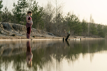 Fototapeta na wymiar Pregnant woman standing at a lake 