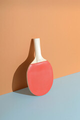 Red ping pong racket leaning against a wall. Sport table tennis still life background concept.