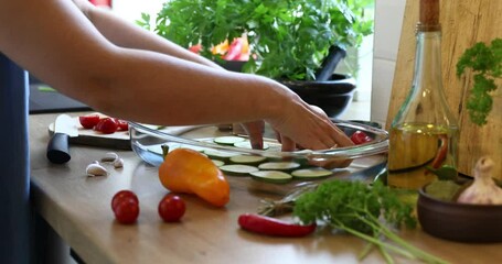 Woman slicing vegetables for cooking on kitchen table. Closeup hands. Close up fresh vegetables on kitchen table. Housewife cooking natural and healthy meal on wooden board.