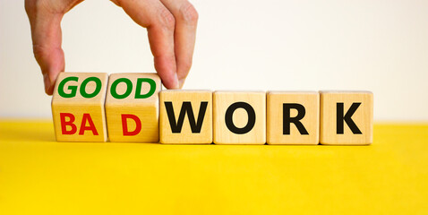 Good or bad work symbol. Businessman turns wooden cubes and changes words 'bad work' to 'good work'. Beautiful yellow table, white background, copy space. Business and good or bad work concept.