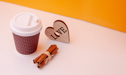 disposable paper cup of coffee next to cinnamon and heart of wood for composition, coffee with you