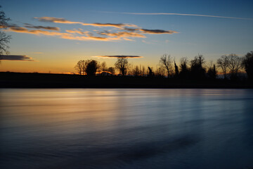 incredible sunset on the Muzza river, lights, colors and reflections surround this breathtaking landscape