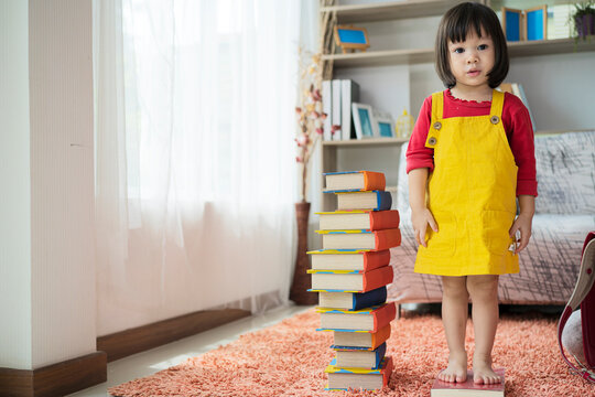 An Asian girl studying in kindergarten stands on a book measuring height