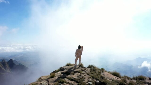 Hiker on top of mountain. Camera go round the woman staying on the edge of the rock. Scenic hike at Drakensberg mountains