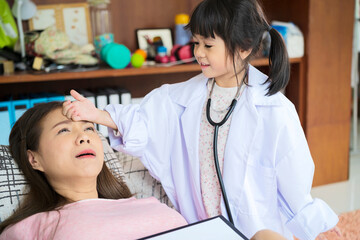 Cute small Asian girl as doctor play with young ethnic mom give injection to patient