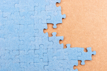 Blue jigsaw puzzle on brown background with copy space. Connected blank puzzle pieces. Business...