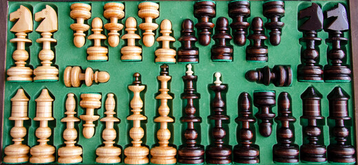 Wooden chess pieces in the playing box with green background