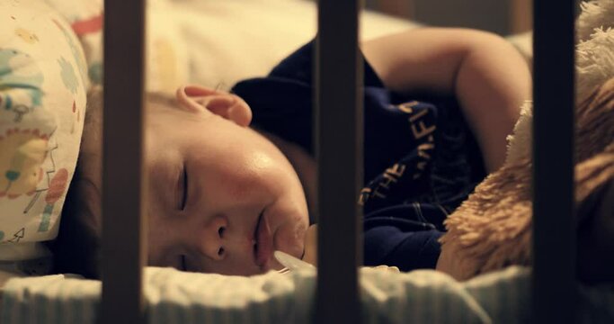 Baby sleeping and crying. Cute baby sleeps in his crib at night under warm lamp light and cries in his sleep. Close-up