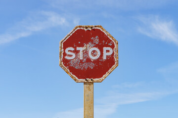Rusty stop sign isolated with blue sky in the background