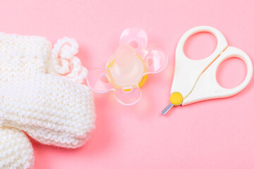 safe scissors, soother and booties for babies on pastel pink background .
