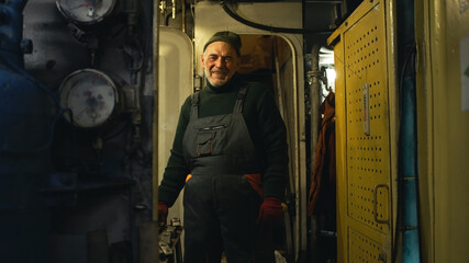 Fototapeta na wymiar Positive aged mechanic working on fishing ship
