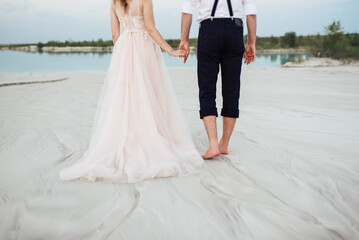 Plakat young couple a guy in black breeches and a girl in a pink dress are walking along the white sand