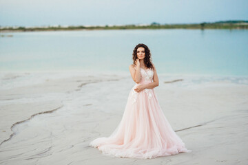 Fototapeta na wymiar girl in a pink dress are walking along the white sand