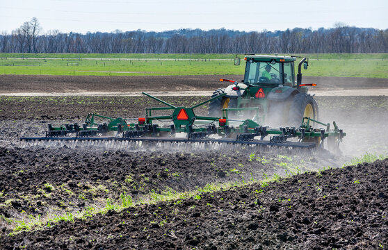 Illinois, USA, April 2, 2021 - Farmer In Tractor Plowing Farm Field Preparing Soil For Spring Corn Planting.