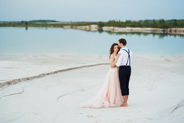 young couple a guy in black breeches and a girl in a pink dress are walking along the white sand - Powered by Adobe