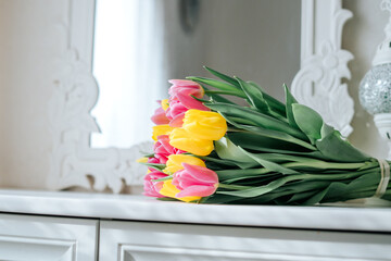 Fresh spring yellow and pink tulips bouquet on white wood table background in mirror with copy space for text. Love, easter, International Women, Mother and Happy Valentine day concept