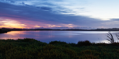 Fototapeta na wymiar The sunrise is reflected in a lake in the False Bay Nature Reserve in Cape Town, South Africa.