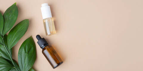 two bottles with pipettes on a beige background, green leaf, top view, banner,natural cosmetics, oil, essence