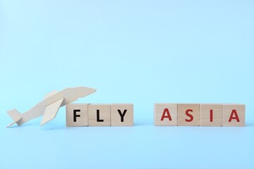 Airplane model and wooden blocks on blue background with copy space. Fly and travel Asia concept. 