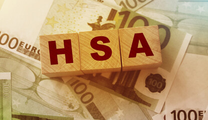 Wooden blocks with the word HSA standing for Health savings account put on 100 Euro bills....