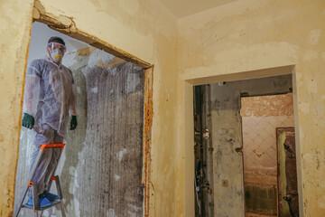 Apartment renovation. The builder in a protective suit, respirator and goggles.