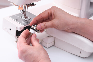 The tailor inserts the spool into the bobbin case of the sewing machine. metal cap