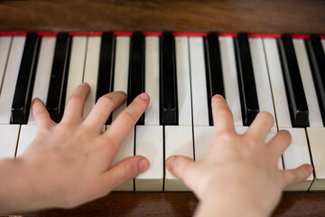 child plays with two hands on ivory piano, horizontal