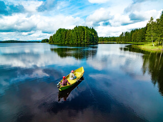 Aerial view of fishing boat with couple in blue summer lake in Finland - Powered by Adobe