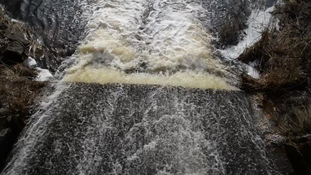 Spring floods.Top down aerial view dirty river with muddy yellow water during floods in spring during heavy rains flows through open locks and floods the shore.water flows through concrete struture
