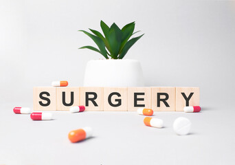 Word SURGERY made from wooden letters on grey backgound. Plant on backgound. Medical concept
