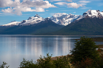 glacier lake in the snowy mountains with reflection and blue sky with clouds 