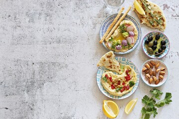 Appetizers table with Hummus,  fresh vegetables, olives and flat bread. Flat layot, copy space