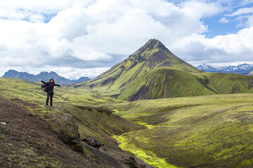 Naklejka na ściany i meble Landmannalaugar, Iceland »; August 2017: A young woman in the incredible landscape of the Landmannalaugar trekking and a mountain in the background.