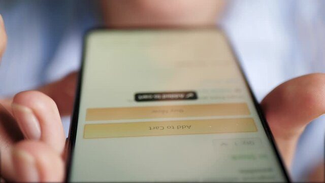 Add to cart, online shopping concept. Female finger taps button ADD TO CART on smartphone screen. Close-up